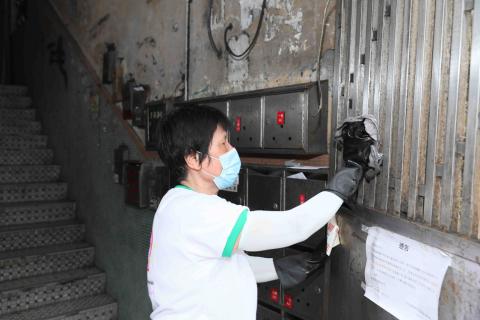 工作人員使用稀釋的漂白水，協助「三無」大廈清抹大廈鐵閘及門口，以減少疾病在本澳社區傳播的風險
