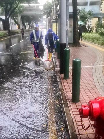 市政署派员处理堵塞排水口落叶，疏通路面积水。
